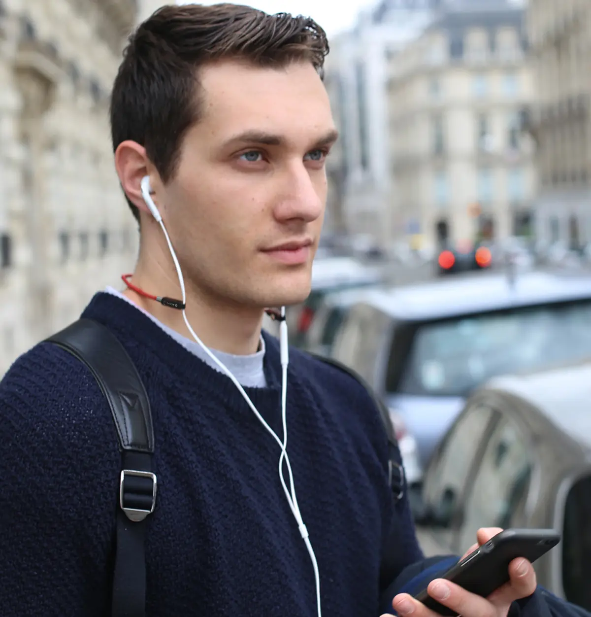 Homme portant SPARK 2.0 dans la rue, écouteurs filaires suspendus au cou